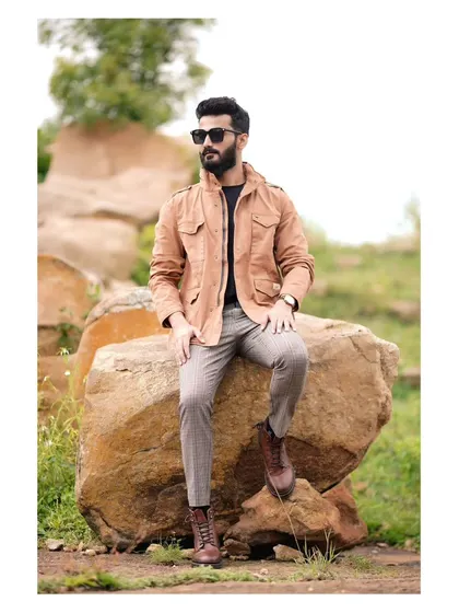 A classic men's fashion-style portrait. The rugged outdoor location, the stylish layering of clothes, and the confident pose make for a strong portfolio image.