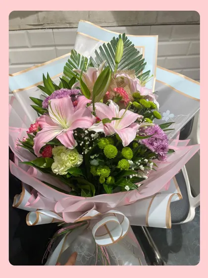 Some fresh blooms to brighten your day. This hand-tied bouquet features pink lilies, purple carnations, and green chrysanthemums, all secured with love and a beautiful wrap.