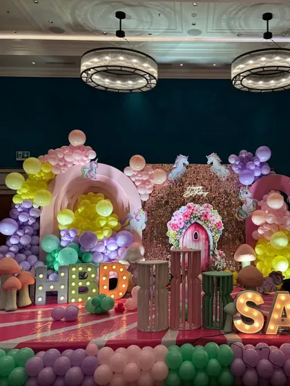 An enchanted garden party with unicorn elements, featuring large mushroom props and pastel balloon clouds.