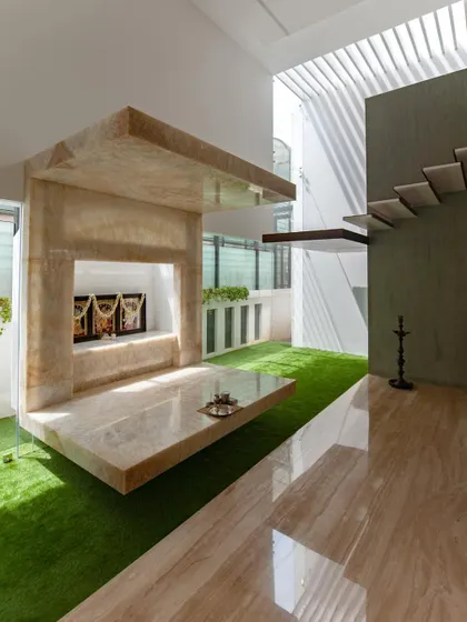A closer look at the cantilevered pooja room, crafted from onyx marble. The design creates a serene, floating sanctuary that is visually connected to the green courtyard and the dining space.