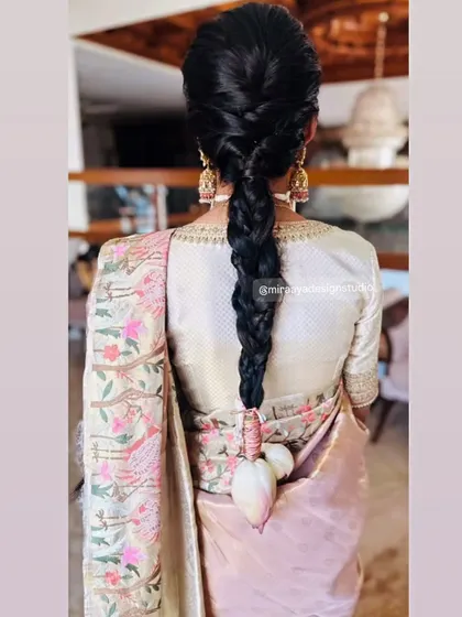A view of the back of Nithya's outfit. The simple, well-fitted blouse provides a perfect canvas for her elaborate hairstyle and the beautiful drape of the saree.