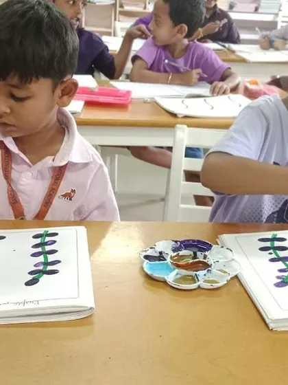 Two students focused on their finger-painting activity, creating beautiful purple lavender stems.