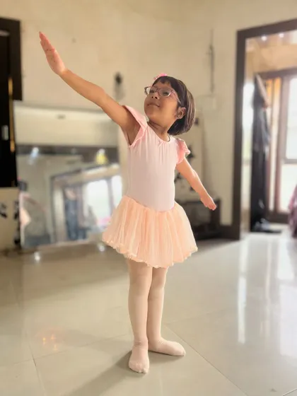 A young student practices her poses in a pink leotard and tutu. Proper attire is encouraged in my ballet classes to help with movement and discipline.