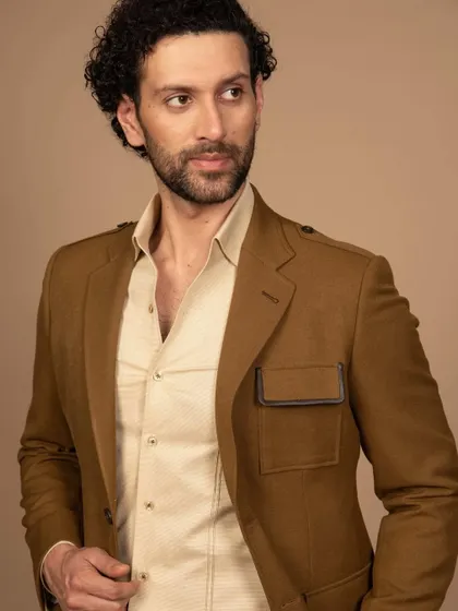A mustard-colored suit with unique leather-trimmed pocket details. This is an example of how I can incorporate unconventional details for a modern, travel-friendly look.