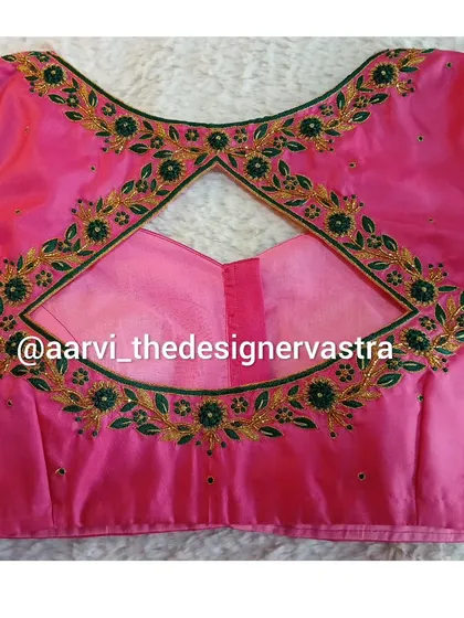 A pink blouse with a diamond shaped keyhole back, framed with green and gold floral embroidery.