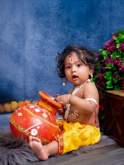 This little Krishna looks surprised while reaching into a painted pot. We aim to capture these spontaneous, story-filled moments that make each festive session unique.