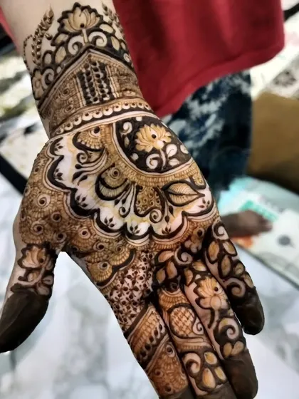 A close-up of a hand with a beautiful reverse-fill floral design. The contrast between the light skin and the dark henna creates a stunning visual impact.