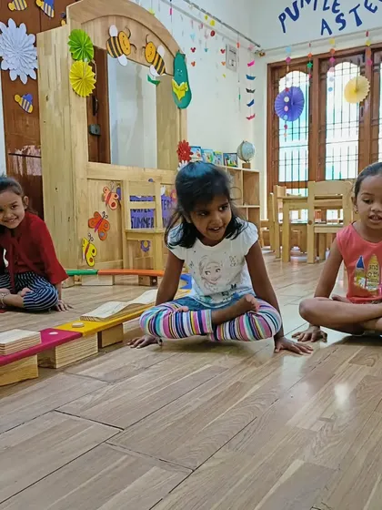 Three girls practice the butterfly pose during a yoga session in our bright and airy classroom.