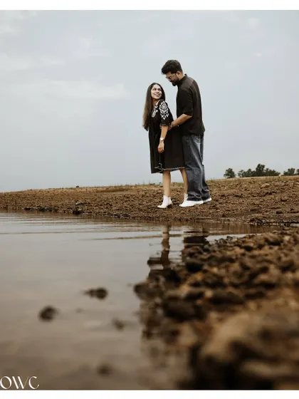 A low-angle shot of a couple by the water, using the reflection to create a unique and artistic composition.