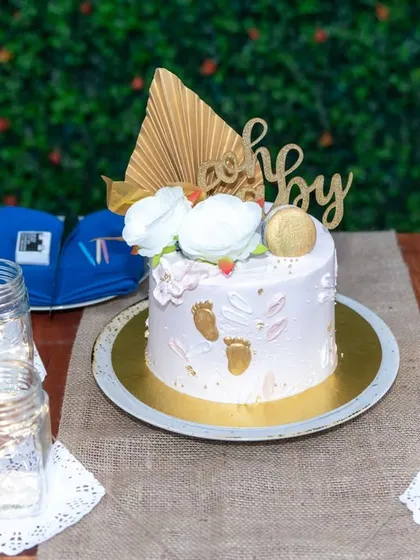 A chic and modern 'Oh Baby' cake for a baby shower, decorated with delicate flowers and gold leaf. We capture the elegance of your event's details.