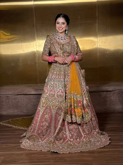 The bride looks radiant and happy in her stunning lehenga. The dupatta is draped neatly to showcase the intricate work on the blouse.