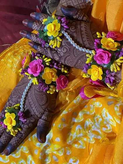 A lovely photo of a bride's hands with the henna stain, adorned with floral jewelry for her Haldi or mehendi ceremony.