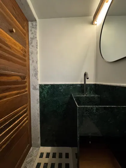 The bathroom in our studio extension features a custom sink and wainscoting made from Baroda Green Marble. This cost-effective, locally sourced stone adds incredible character and depth to the small space.