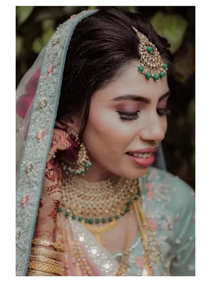 A close-up portrait of a bride, highlighting her stunning makeup and the intricate details of her jewelry.