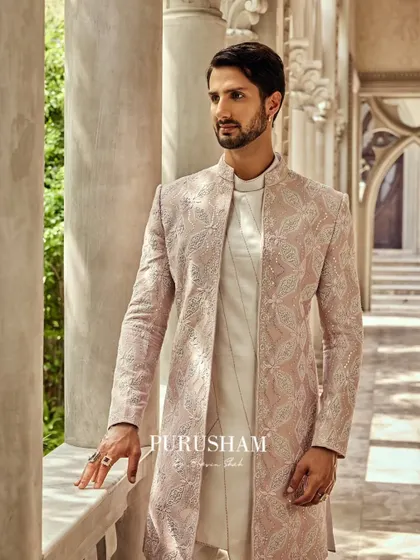 This dusty rose sherwani offers a contemporary take on wedding wear. The full-body, single-tone embroidery creates a rich texture, layered over a simple white kurta for a look that is memorable and sophisticated.