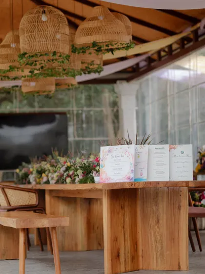A close-up of a rustic wooden table with a beautiful floral runner and personalized wedding stationery.