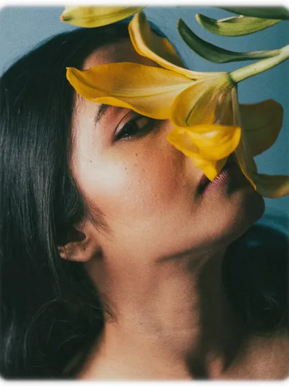 An artistic shot where a flower petal covers one eye, playing with perception and beauty.