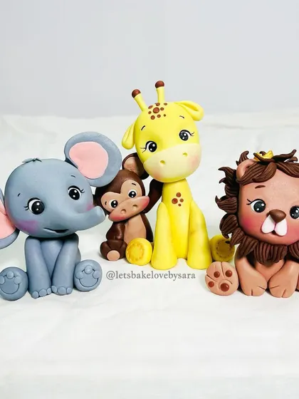 Meet the family. This adorable set of four fondant jungle animals, featuring an elephant, monkey, giraffe, and lion, are all handcrafted with love and ready to top a special birthday cake.