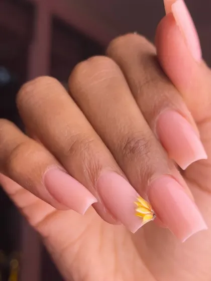 A single, delicate daisy painted on a perfectly shaped nude pink nail. This design is a beautiful example of minimalist floral art.