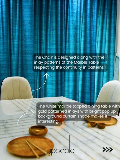 In this dining space, we used a bright cobalt blue curtain to create a bold background. The white marble-topped table features gold patterned inlays, and the chairs are designed to echo the inlay pattern, ensuring continuity.