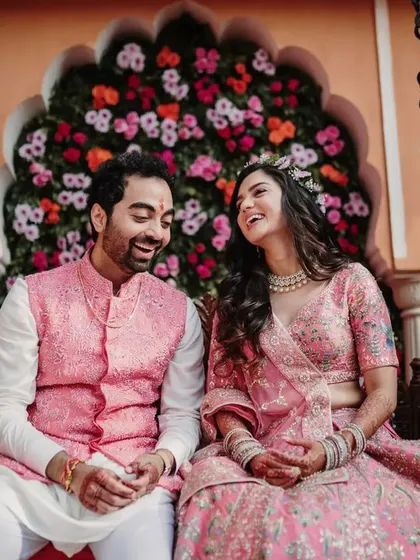 A candid moment of laughter shared between the couple on a floral swing. This image from their Mehendi ceremony is full of color, joy, and natural chemistry.