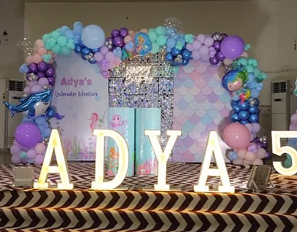 We dove deep to create Adya's underwater adventure for her fifth birthday. This setup features a mermaid-scale sequin backdrop, balloon arrangements in ocean hues of aqua and purple, and character cutouts to bring her under-the-sea dream to life.