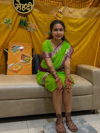 The beautiful bride looking lovely in her green saree, seated at her mehendi ceremony.
