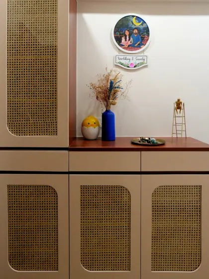 A cozy and welcoming entrance featuring a modern shoe rack with natural rattan panels. The quirky decor accents and a personalized portrait on the wall make the space feel warm and instantly like home.