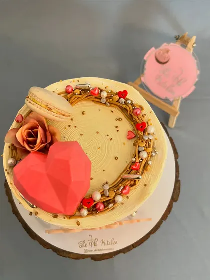 A top-down view of the anniversary wreath cake, showing the detailed arrangement of sprinkles, hearts, and a delicate macaron.