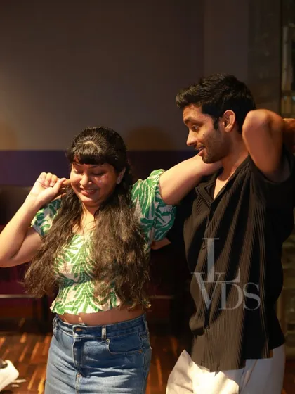 A playful moment on the dance floor, with a woman laughing as her partner teaches her a move.