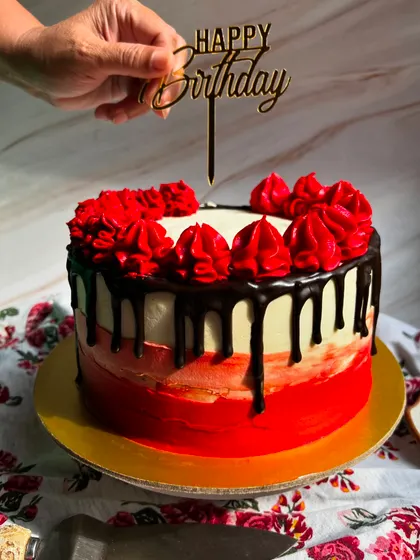 Adding the final touch. A "Happy Birthday" topper is placed on our red and black themed chocolate truffle cake.