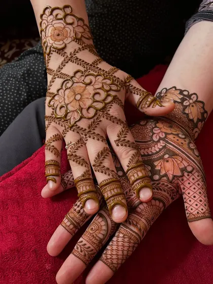 A beautiful example of a jaal (net) design combined with floral elements. The criss-cross pattern creates an elegant glove-like effect, while the flowers add a touch of softness to this party mehndi look.