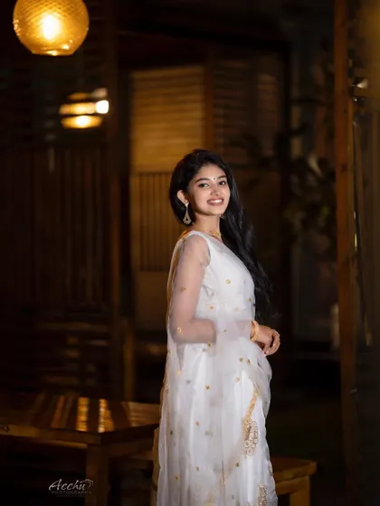 The warm, glowing lights in the background create a beautiful bokeh effect. This nighttime portrait in a white lehenga feels magical and romantic.