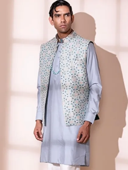A classic men's ethnic look featuring a powder blue kurta paired with a beautifully embroidered Nehru jacket. The subtle jewellery adds a touch of personal style.