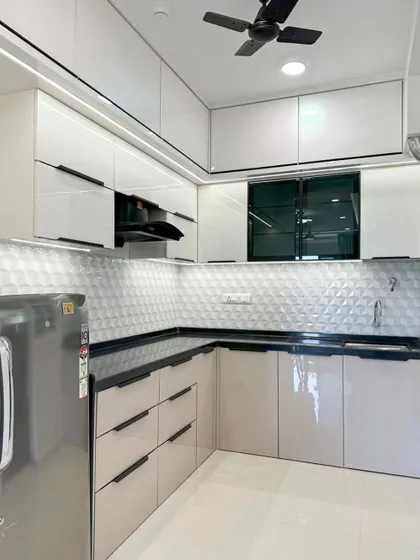 Another view of the L-shaped kitchen, showing the integrated refrigerator and the ample storage provided by the floor-to-ceiling cabinets.