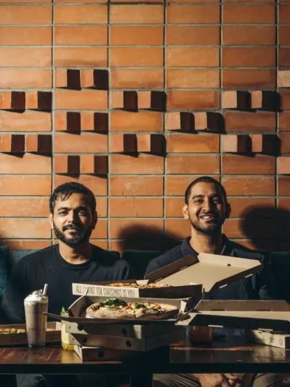 The founders surrounded by pizzas at a Christmas celebration. It's a reflection of the family and community we've built around our brand.