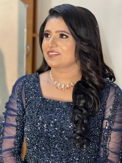 A client ready for an evening event in a sparkling blue gown, with her hair styled in glamorous side-swept waves.