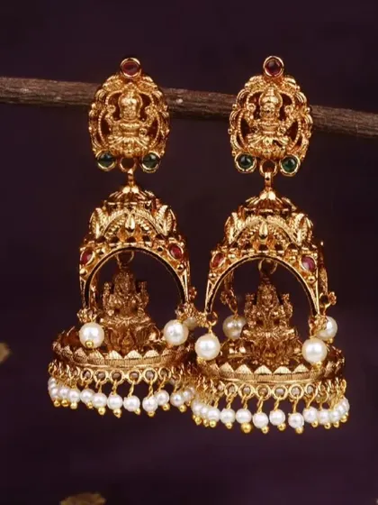 The same traditional matte gold finish jhumki, but this version is adorned with classic white pearls. This is a timeless choice for pairing with silk sarees.