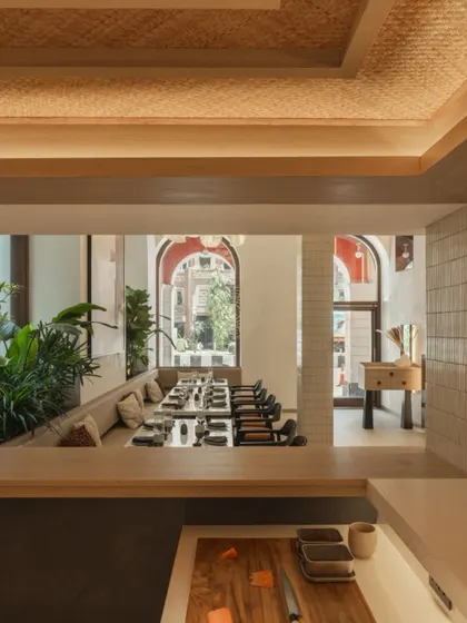 From behind the sushi bar, you can see through to the main dining area, creating a sense of connection between the chefs and the guests. The ceiling features a textured wood finish.