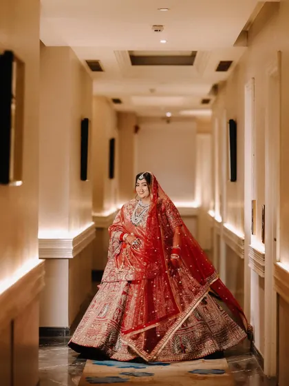 Using the leading lines of the hotel corridor, I framed the bride to create a powerful and elegant portrait. Her red lehenga fills the frame, making her the undeniable center of attention.
