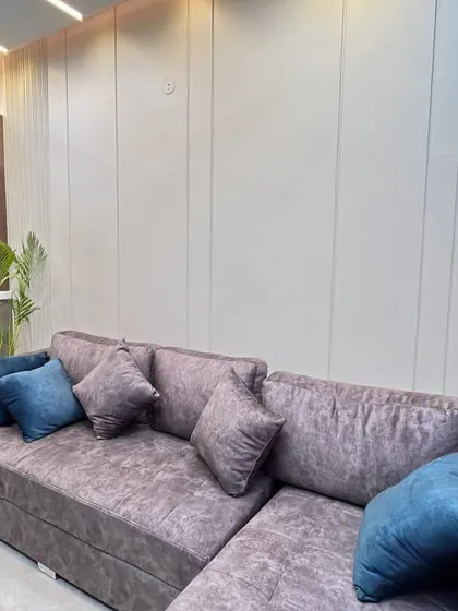 A custom L-shaped sofa with contrasting cushions, set against a simple wall with vertical grooves for a subtle design element.