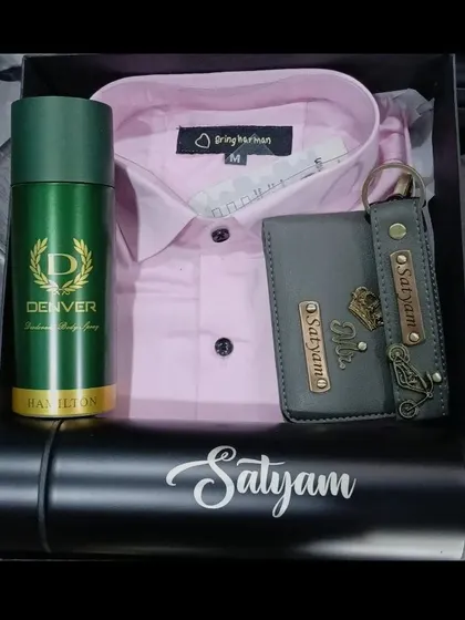 This gift hamper combines a pink shirt with a personalized grey wallet and keychain, a name-engraved bottle, and deodorant.