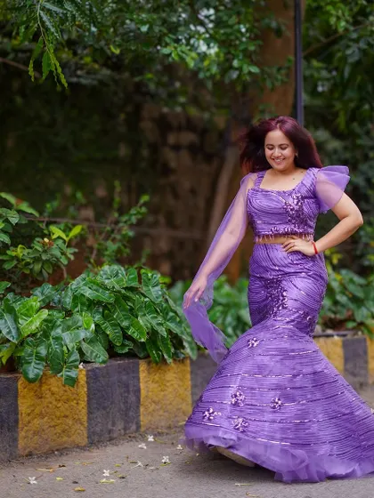The purple sequined mermaid gown in a garden setting. The color and sparkle make it a standout piece.
