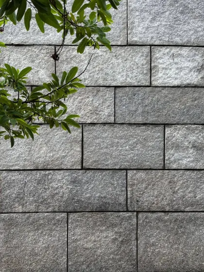 A sample of a granite wall, showing the precise joinery and textured finish of the stone. We work closely with stonemasons to select and craft each block, celebrating the natural beauty of the material.