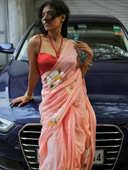 An urban take on saree modeling, pairing a soft floral saree with a modern car to create a contrasting, edgy look for contemporary fashion campaigns.