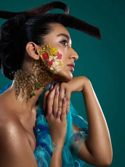 A profile view from the 'Roots' editorial, highlighting the sculptural hair and the organic texture of the floral makeup.