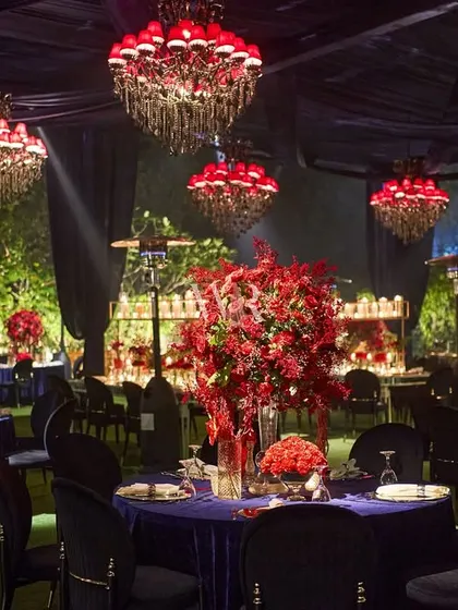 For this cocktail night, we created a secret world of red and blue. The space was defined by deep blue velvet tablecloths and dramatic red chandeliers, with lush red floral centerpieces adding to the passionate and opulent atmosphere.