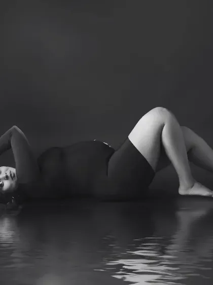 An artistic black and white portrait with a water reflection, creating a moody, high-fashion look.