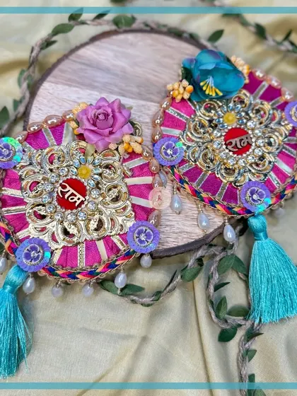 This magenta "Ram Ram" design with turquoise tassels is a vibrant and colorful choice for your Rakhi celebrations.