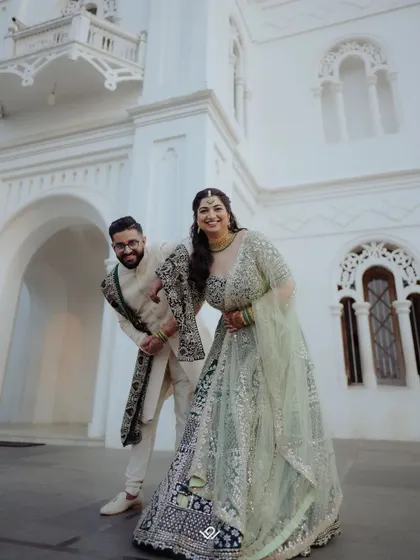 A fun and candid shot of a couple outside a grand white building, sharing a laugh.